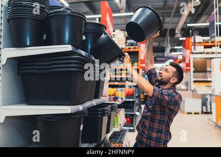 Ein Mann in einem Baumarkt wählt Baueimer Stockfoto