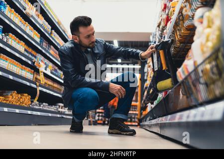 Ein Mann in einem Baumarkt wählt eine Rolle und einen Behälter für Farbe Stockfoto