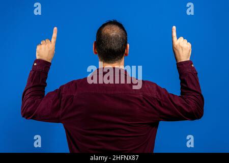 Hispanischer Mann mit Bart und lässigem T-Shirt, der mit den Fingerhände nach oben zeigt. Stockfoto