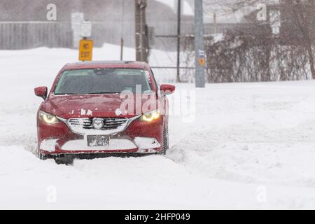 Ein rotes Mazda-Auto dreht sich während eines Winterschneesturms in Toronto, Kanada, von der schneebedeckten Victoria Park Avenue in Richtung des nicht freigedeckten Terraview Blvd Stockfoto