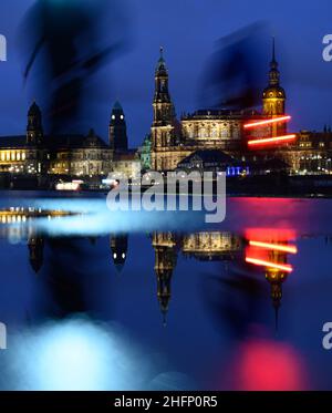 Dresden, Deutschland. 17th Januar 2022. Fußgänger und Radfahrer befinden sich abends auf dem Elbradweg vor der Altstadtkulisse mit dem Ständehaus (l-r), dem Rathaus, der Hofkirche, dem Hausmannsturm, dem Italienischen Dorf und dem Residenzschloss und spiegeln sich in einer Pfütze wider. (Aufnahme mit langer Belichtungszeit) Credit: Robert Michael/dpa-Zentralbild/dpa/Alamy Live News Stockfoto