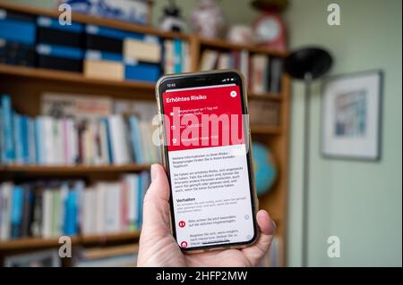 Eine Hand hält ein Smartphone mit einer Infektionswarnung im Corona-App Display Stockfoto