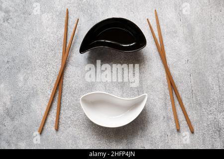 Auf dem betton-Tisch liegen Keramik-Yin-Yang-Schüsseln und hölzerne Bambusstäbchen Stockfoto