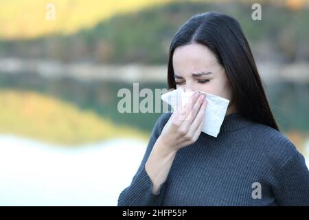 Kranke Frau, die im Winter mit einem Gewebe in die Nase bläst Stockfoto