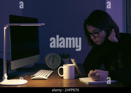 Eine junge Frau, die nachts am Arbeitsplatz arbeitet. Stockfoto