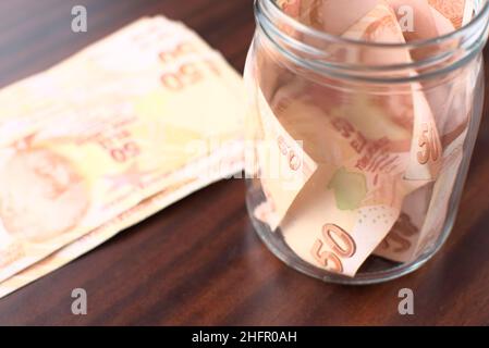 Etwa 50 türkische Liras in einem Glas auf braunem Hintergrund zu retten. Stockfoto