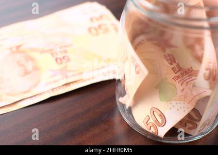 Etwa 50 türkische Liras in einem Glas auf braunem Hintergrund zu retten. Stockfoto