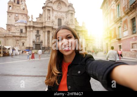 Tourist Girl in Murcia, das Selfie-Foto mit der Kathedrale Kirche Santa Maria und Stadtbild auf dem Hintergrund. Mädchen porträtiert sich in Murcia Stockfoto