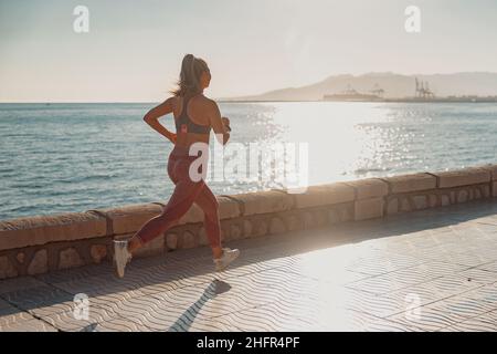 Sportliche, hübsche Frau, die aktiv am Wasser läuft Stockfoto