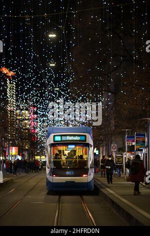 Zürich, Schweiz - 12 2021. Dezember: Eine Straßenbahn fährt entlang der Bahnhofstrasse, der Hauptstraße in der Zürcher Innenstadt mit weihnachtlicher Dekoration Stockfoto