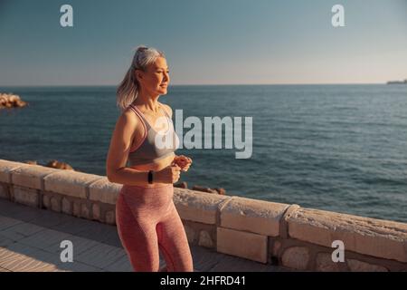 Sportliche Frauen mit Erwachsenen trainieren am Wasser Stockfoto