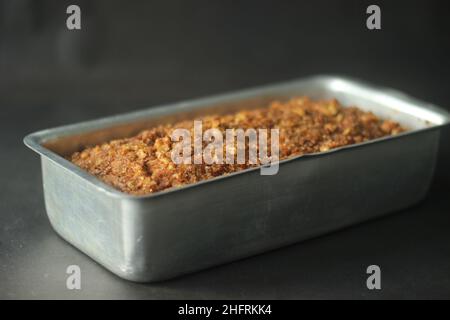 Bananenbrot aus Vollkornmehl und Kokosöl. Gebacken mit Zimt, Zucker und Walnuss für einen knusprigen Top. Frisch aus dem Ofen serviert in einem Rectangu Stockfoto