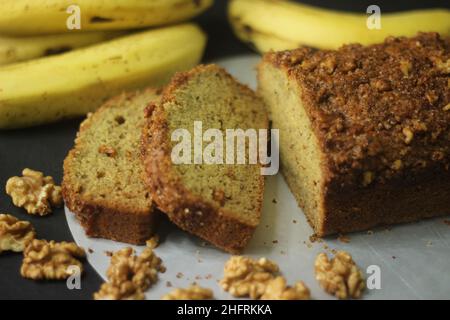 Bananenbrot aus Vollkornmehl und Kokosöl. Gebacken mit Zimt, Zucker und Walnuss für einen knusprigen Top. In Scheiben geschnittenes Bananenbrot, das mit Banane geschossen wurde Stockfoto