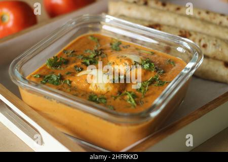 Eierbutter-Masala. Gekochte Eier werden zu einer reichen Soße aus Zwiebeln, Tomaten, Cashewnüssen und Gewürzen mit kasuri-Methi hinzugefügt. Serviert mit indischem Fladenbauch Stockfoto