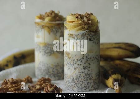 Über Nacht Hafer mit reifen Kochbananen und Walnüssen. Hergestellt durch Einweichen gerollter Hafer und Chiasamen in Milch, serviert mit geschnittenen Kochbananen, Walnüssen und gesüßt Stockfoto