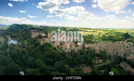 Panorama-Luftaufnahme von Castell'Arquato mittelalterlichen Stadt in Piacenza Italien mit Ziegelhäusern Wolken schönen Himmel und Wald Stockfoto