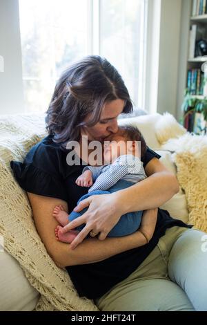 Die liebevolle Mutter küsst ihren Sohn zu Hause auf die Stirn. Stockfoto