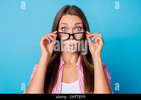 Foto von neugierigen schockiert junge Dame nehmen Brillen offenen Mund tragen rosa gestreiftes Hemd isoliert blauen Hintergrund Stockfoto