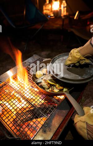 Männliche Hände kochen in einem Gusseisen über einem offenen Feuer. Stockfoto