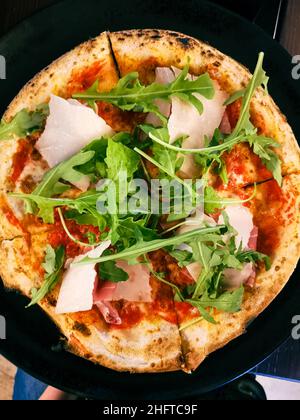 Draufsicht auf Pizza mit frischem Parmesan und Rucola in vier Stücke geschnitten Stockfoto