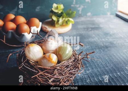 Farbige Onyx-Kugeln in einem echten Vogelnest mit natürlichem Licht aus dem Fenster. Ostereier aus natürlichem Onyx-Edelstein. Modische Organisation von Stockfoto