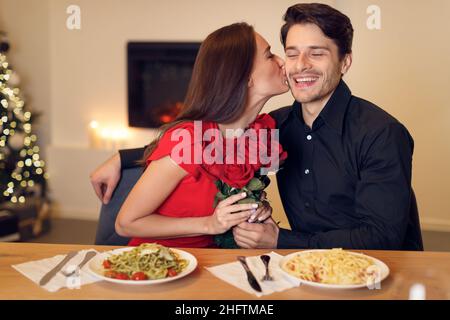 Junge Frau küsst ihren Mann mit Blumen Stockfoto