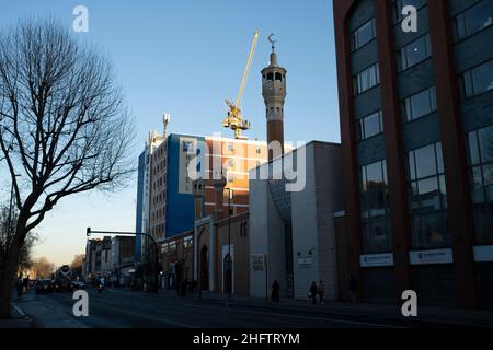 East London Mosque an der Whitechapel High Street am 13th. Januar 2022 in London, Großbritannien. Die East London Mosque ELM befindet sich im Londoner Stadtteil Tower Hamlets zwischen Whitechapel und Aldgate East. Zusammen mit dem angrenzenden London Muslim Center und dem Maryam Center ist es eine der größten Moscheen in Europa und die größte in Großbritannien, in der mehr als 7.000 Gläubige für Gemeindegebete Platz finden. Whitechapel, ein sehr ethnisch vielfältiges und pulsierendes Viertel im East End, beherbergt eine bedeutende Bevölkerung von Einwohnern Bangladeschs. Dies ist entlang des Gehweges zu sehen Stockfoto