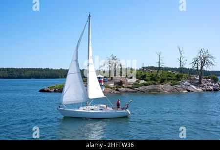 Mann und sein Segelboot segeln an einem schönen Sommertag im Stockholmer Archipel Stockfoto