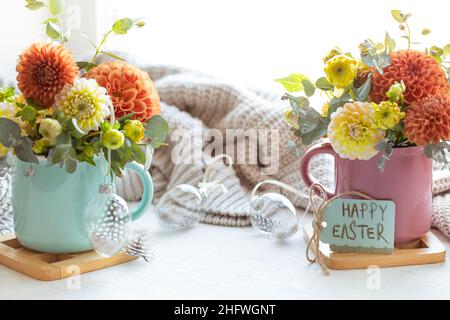 Osterkomposition mit einem Blumenstrauß und einem gestrickten Element. Stockfoto