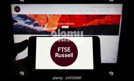 Person, die ein Mobiltelefon mit dem Logo des britischen Unternehmens FTSE Russell (LSEG) auf dem Bildschirm vor der Unternehmenswebseite hält. Konzentrieren Sie sich auf die Telefonanzeige. Stockfoto