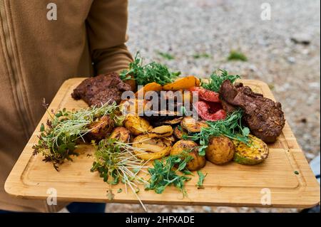 Nahaufnahme von Rippchen vom Grill mit BBQ Sauce und karamellisierten in Honig. Leckeren Snack zum Bier auf einem Holzbrett für die Einreichung auf dunklen konkreten Hintergrund Stockfoto