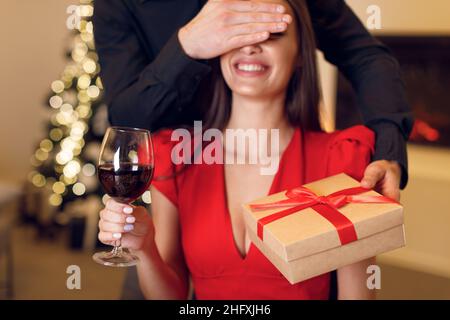 Junger Mann, der der Frau eine Schachtel gab und die Augen bedeckte Stockfoto