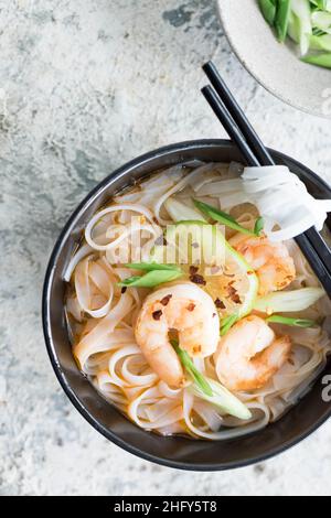 Asiatische Suppenramen mit Nudeln mit Miso-Paste, Sojasauce, Grüns und Garnelengarnelen. Auf einem grauen Betontisch mit Essstäbchen. Draufsicht. Japanisches Essen Stockfoto