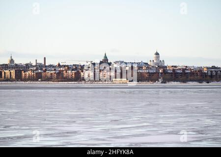 Helsinki / Finnland - 13. JANUAR 2022: Blick auf die Innenstadt von Helsinki von der anderen Flussseite an einem sonnigen Wintertag. Stockfoto