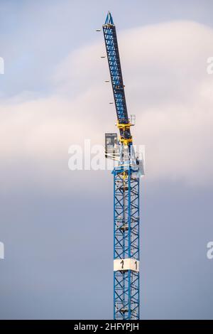 Helsinki / Finnland - 13. JANUAR 2022: Ein moderner Baukran gegen den bewölkten Himmel an einem sonnigen Wintertag. Stockfoto