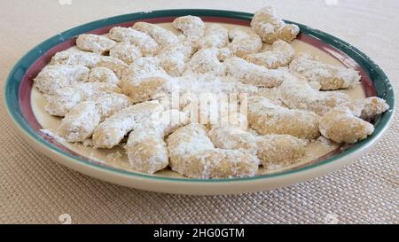 Platte mit hausgemachten mexikanischen Hochzeitsplätzchen, die mit Puderzucker bestäubt sind und fertig zum Essen ausgelegt sind: Pekannuss, Walnuss, Mandelknüsse. Stockfoto