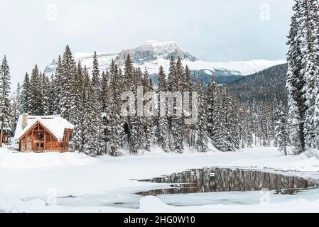 Yoho National Park, Kanada - 23 2021. Dez.: Holzhütte und cabane an der Seite des Frozen Emerald Lake, versteckt im Winterwald, umgeben von rockies Mount Stockfoto