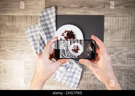 Mann, der mit dem Smartphone Fotos von Lebensmitteln gemacht hat Stockfoto