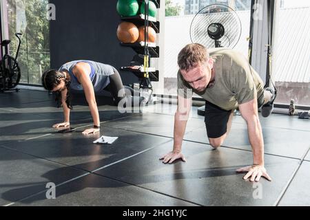 Paartraining mit Aufhängegeräten im Fitnessstudio in Bangkok Stockfoto