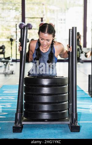 Frau, die im Fitnessstudio in Bangkok den Schlitten schiebt Stockfoto