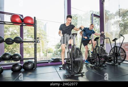 Zwei Männer trainieren auf Heimtrainern im Fitnessstudio in Bangkok Stockfoto