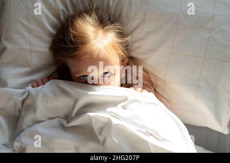 Das kleine Mädchen wachte am Morgen im Bett auf Stockfoto