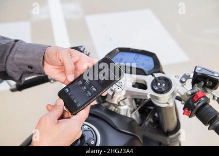 Techniker überprüft Elektromotorrad mit Smartphone in der Werkstatt Stockfoto