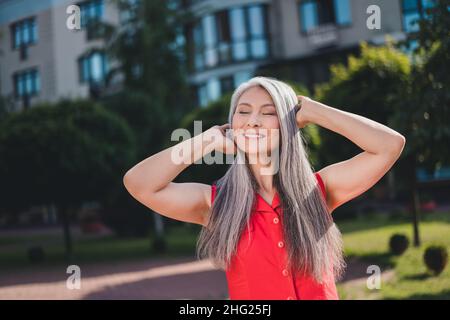 Porträt einer attraktiven verträumten, fröhlichen grauhaarigen Frau, die bei sonnigem Wetter am Wochenende im Freien Freizeit verbringt Stockfoto