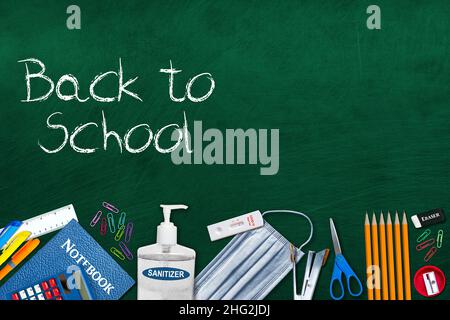 Zurück zur Schule Grundkonzept in der neuen Normalität während der Covid-19 Pandemie mit Schnelltest-Kit, Händedesinfektionsmittel, Gesichtsmaske und Papeterie auf Chalkboa Stockfoto