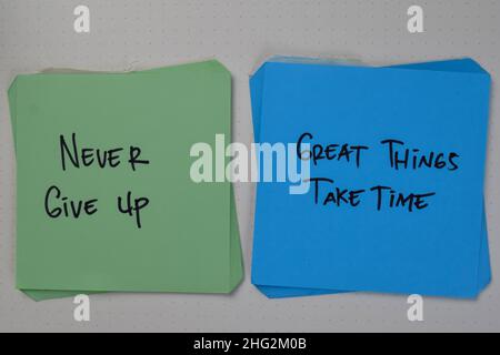 Geben Sie nie auf - große Dinge brauchen Zeit Schreiben Sie auf Haftnotizen isoliert auf Holztisch. Stockfoto