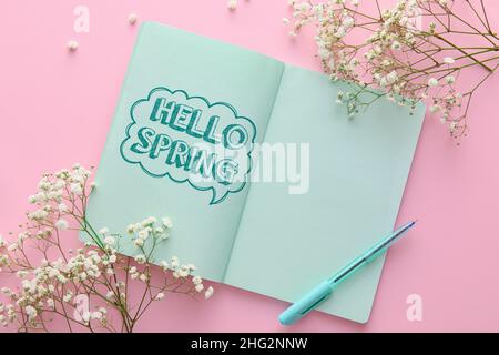 Notizbuch mit Text HALLO FRÜHLING und Blumen auf rosa Hintergrund Stockfoto