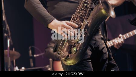 Saxophonist bei einem Konzert spielt Saxophon. Es ist dunkel Stockfoto