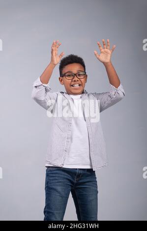 Kind in einer Brille, die seine Hände hebt und nach vorne blickt Stockfoto