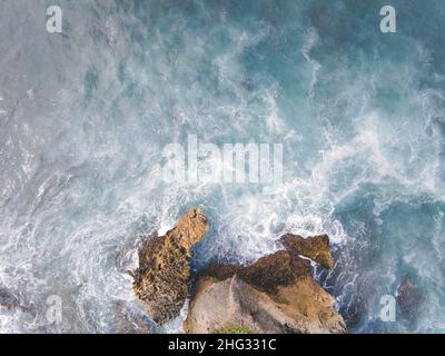 Von oben aus hat man eine Luftaufnahme der riesigen Meereswellen, die am Korallenstrand zusammenbrechen und schäumen Stockfoto